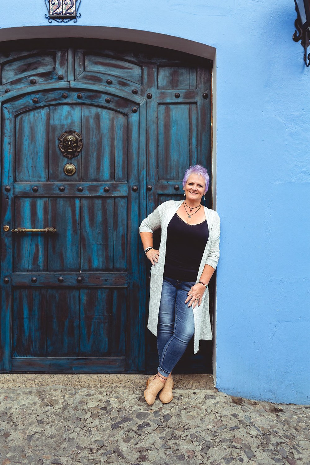 Ronda Taylor smiling in a doorway beside a rustic blue door in Antigua, Guatemala